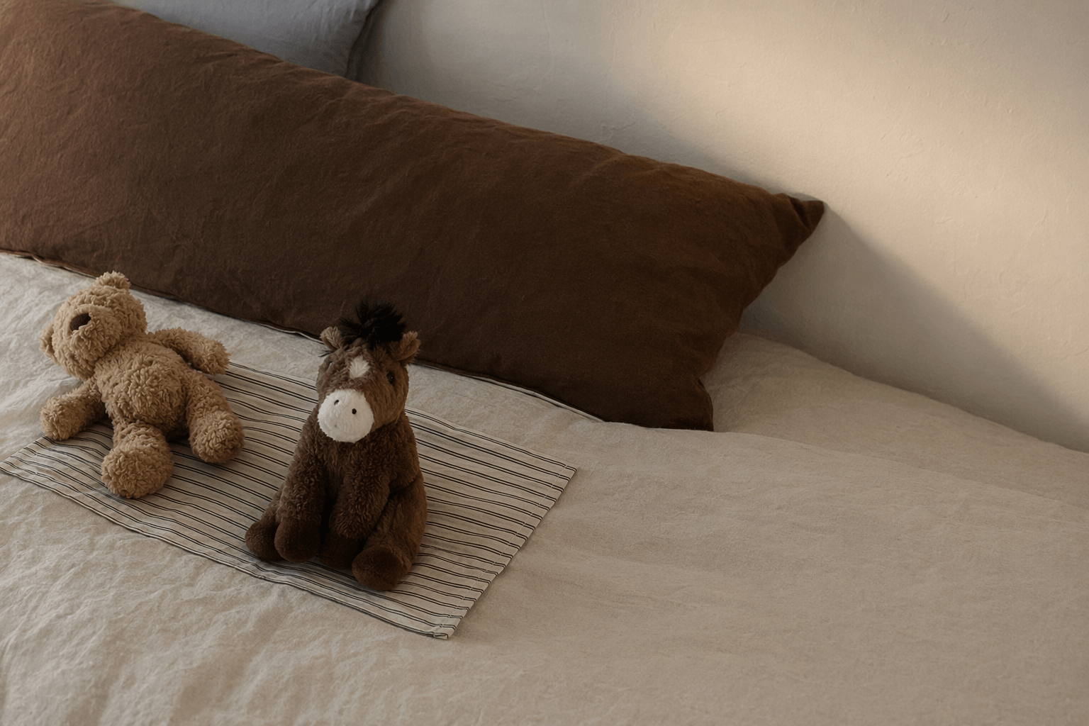 Baby bedding and cotton essentials arranged in a calm, warm home.